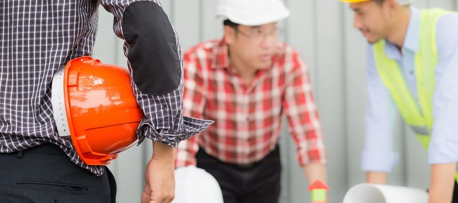 engineer and construction team wearing safety helmet and looking blueprint on the table