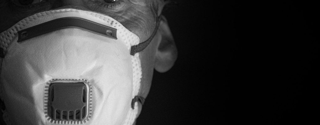 An elderly man wears a face mask