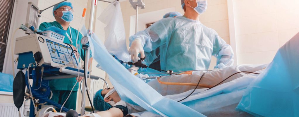 Doctors in a hospital room perform surgery on a patient.