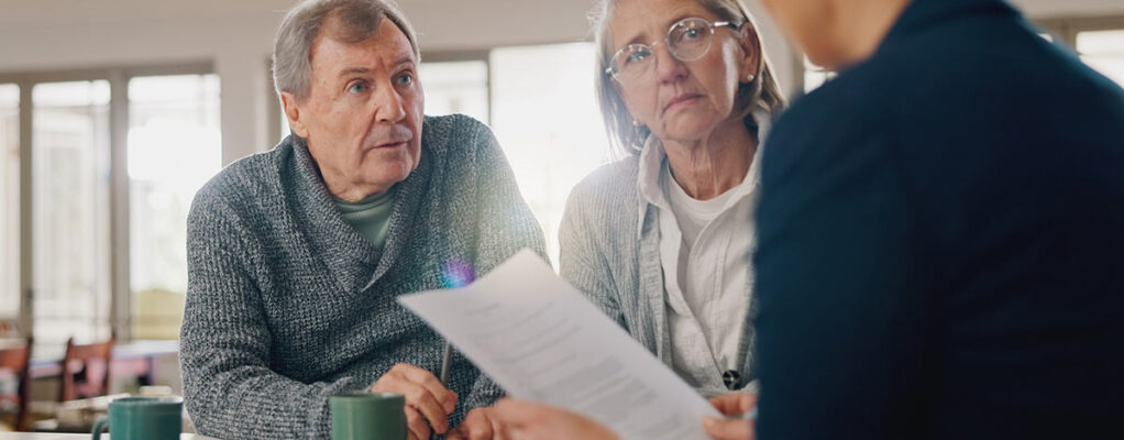 An older man and woman meet with an attorney
