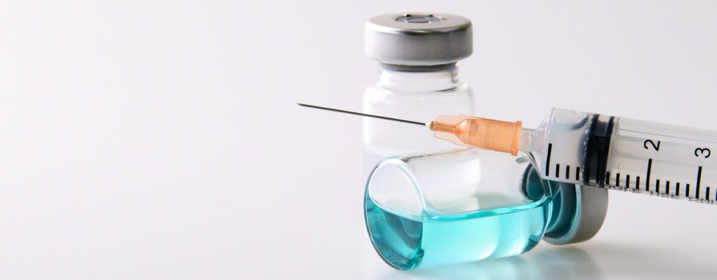 a needle resting on a bottle of fluid