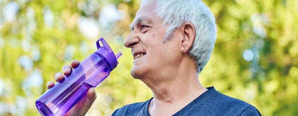 Older man outside holding a plastic bottle filled with water