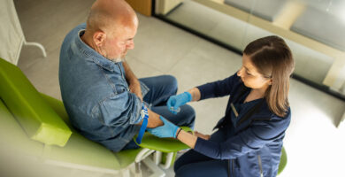 Older man getting ready to get his blood drawn by a nurse in a clinic