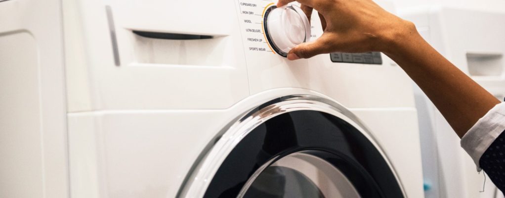 A hand moving a washing machine dial