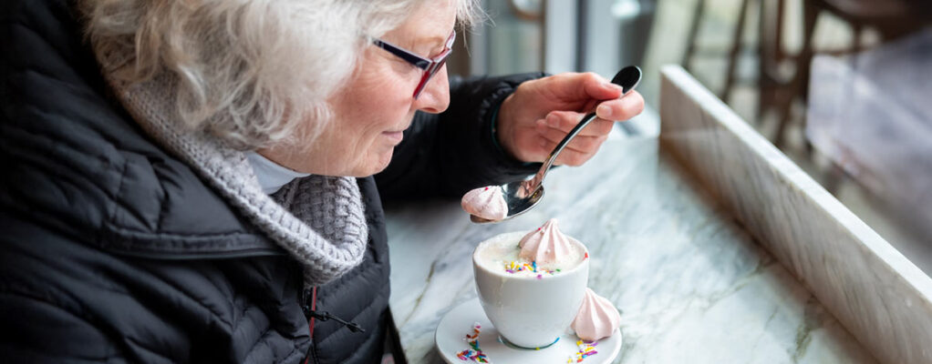 An older woman enjoying a sugary coffee with whipped cream