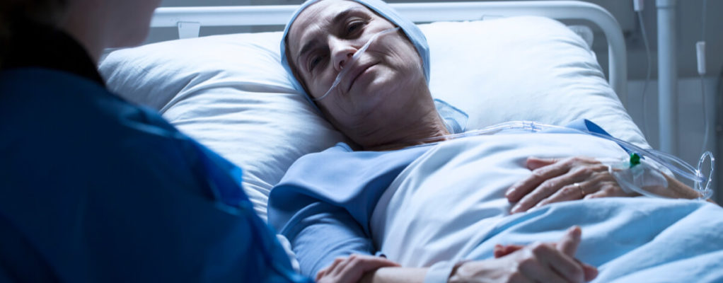 a woman lies in a hospital bed while receiving cancer treatment