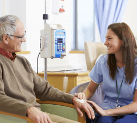 A nurse sits with a patient who is receiving intravenous mesothelioma chemotherapy
